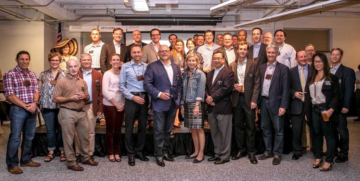 Group photo of approximately 30 business professionals standing together in an indoor office setting